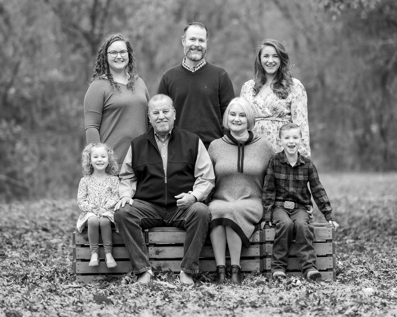 Black and white family photos. Grandparents, children, and grandchildren sitting on a bench in the forest.