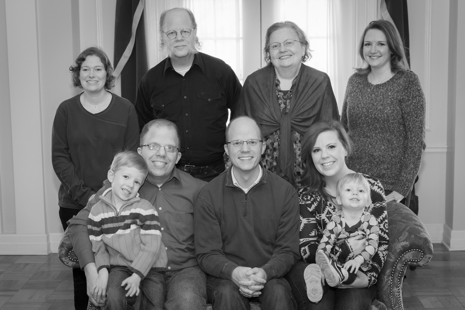 Black and white family photos. Grandparents, their children, and two grandchildren sitting on a sofa in a formal setting.