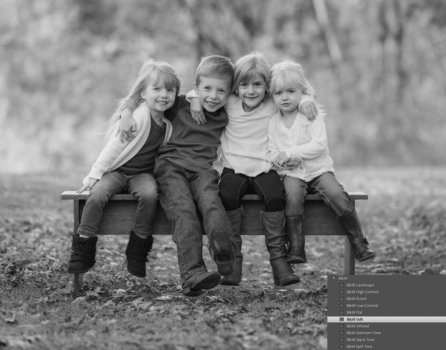 Black and white family photos. Four children sitting on a bench in the forest.