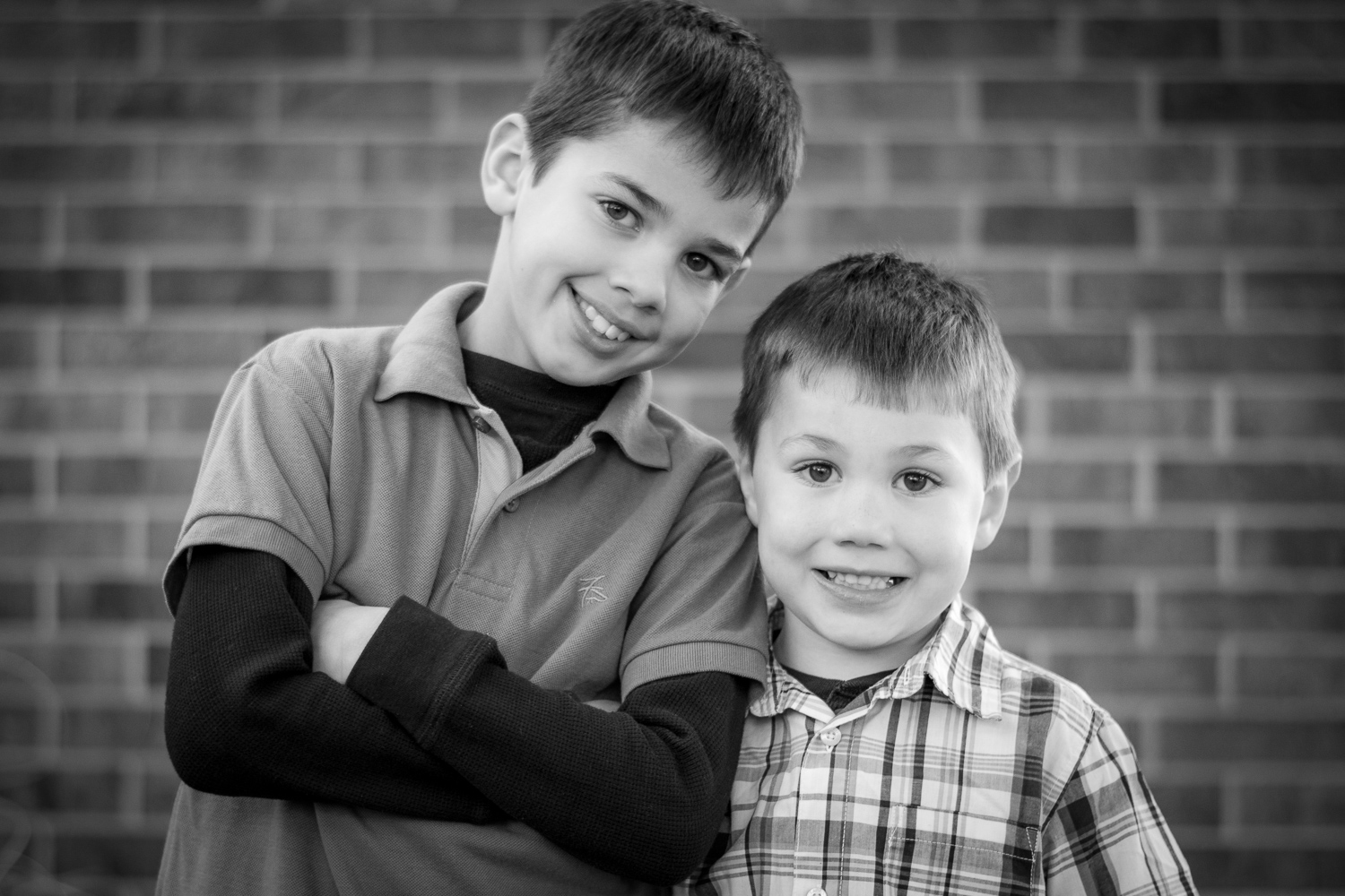 Black and white family photos. Two young boys standing next to each other and looking at the camera while smiling.