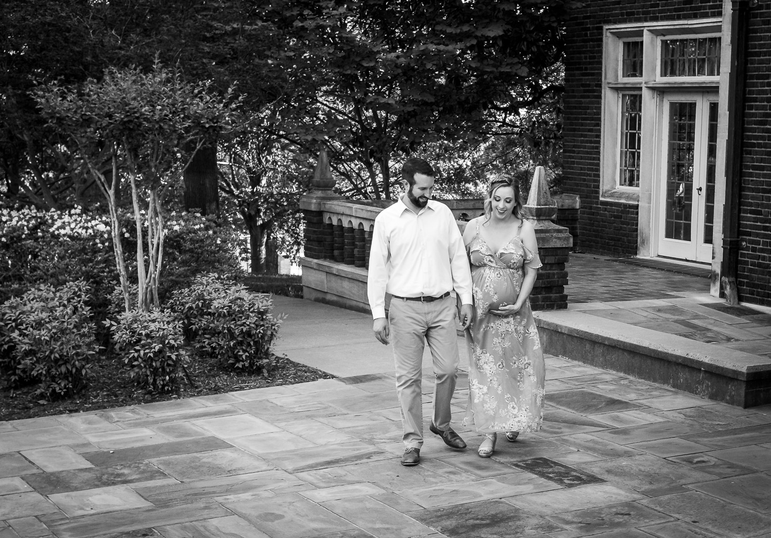 Black and white family photos. Husband and wife walking across pavement in front of an old house.